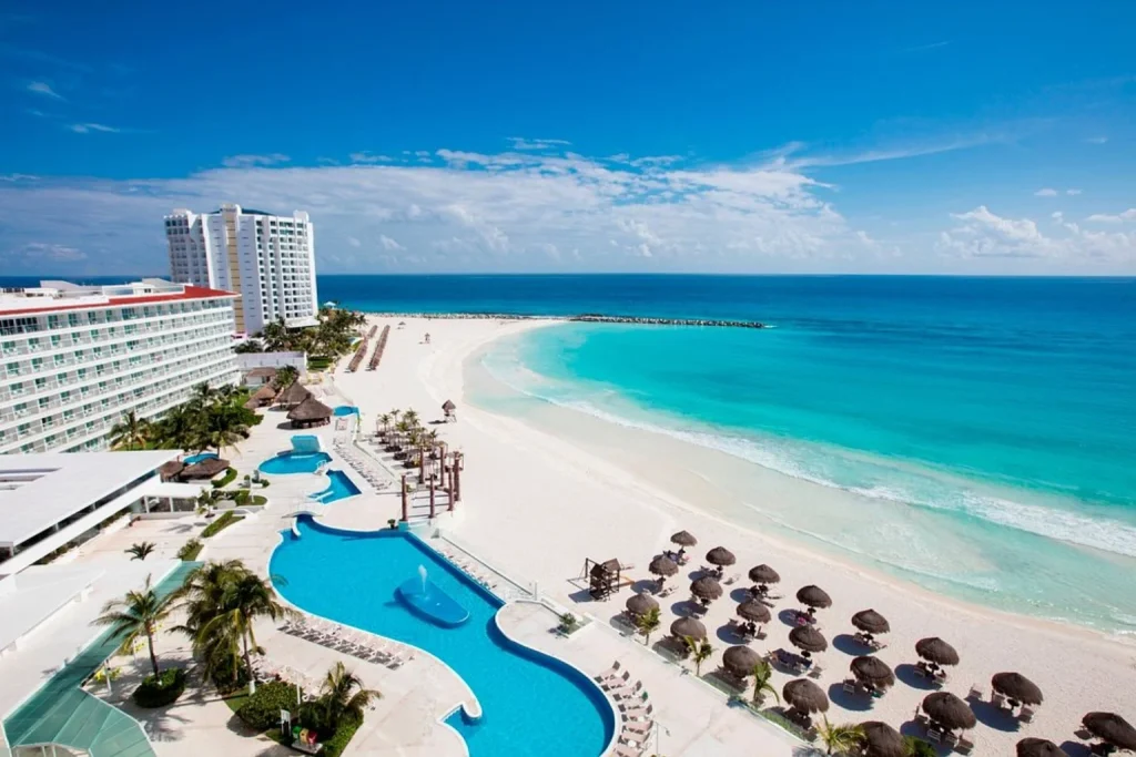 Curved resort pools beside a wide white-sand beach and turquoise Caribbean waters, Krystal Cancun, Cancun