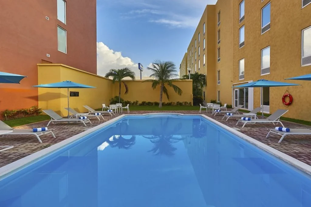 Outdoor pool with sun loungers at City Express Junior by Marriott Cancun in Cancun, Mexico