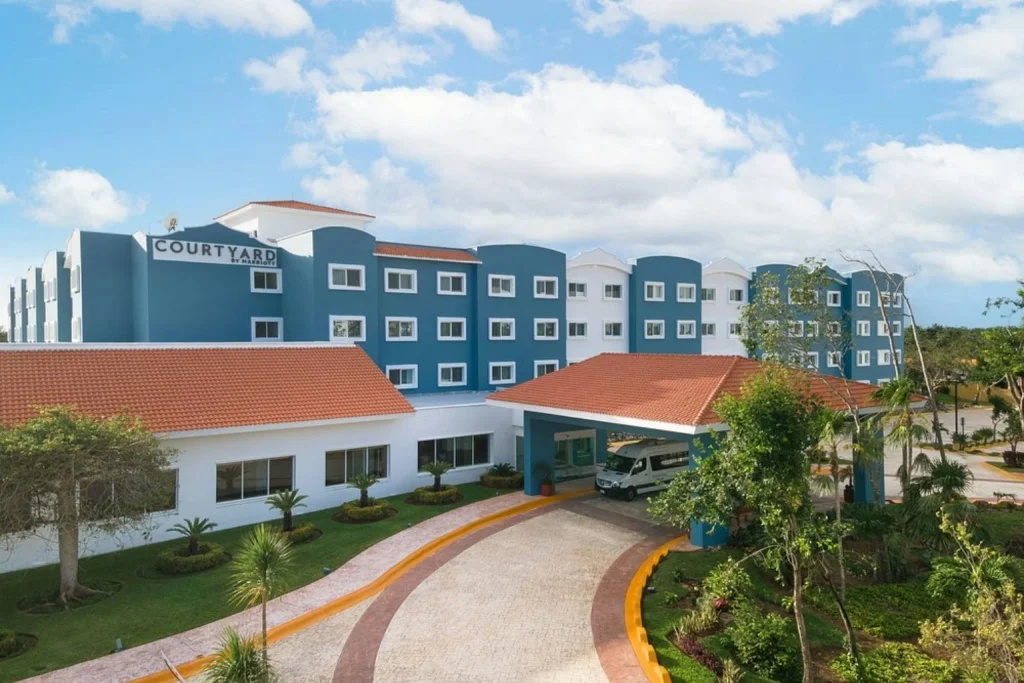 Exterior view of the hotel with its main entrance, landscaped gardens and driveway at Courtyard by Marriott Cancun Airport in Cancun.