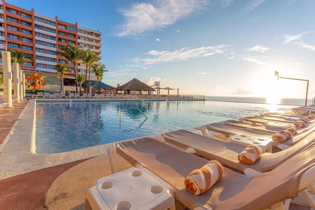 Beachfront infinity pool with sun loungers overlooking the Caribbean Sea at Crown Paradise Club Cancun in Cancun, Mexico.