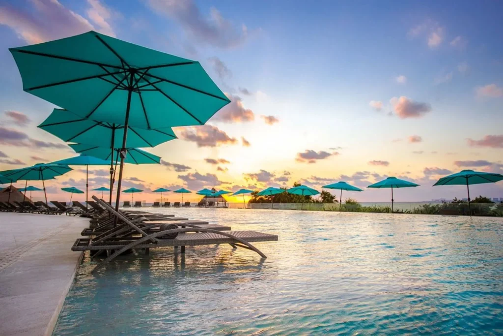 Infinity pool with in-water loungers and panoramic sunset views at Dreams Vista Cancun Golf & Spa Resort in Cancún, Mexico.