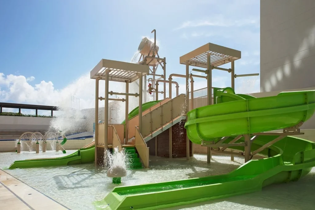 Water play area with green slides and splash features at Dreams Vista Cancun Golf & Spa Resort in Cancún, Mexico