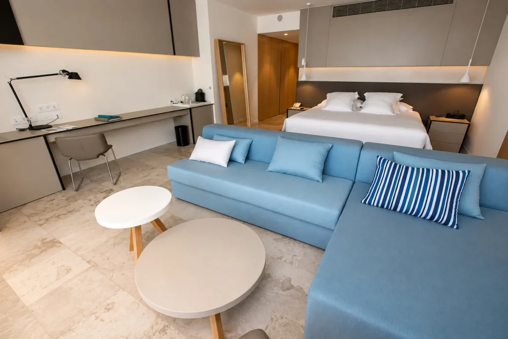 Family suite with king bed and blue sofa at Finest Playa Mujeres in Playa Mujeres, Mexico