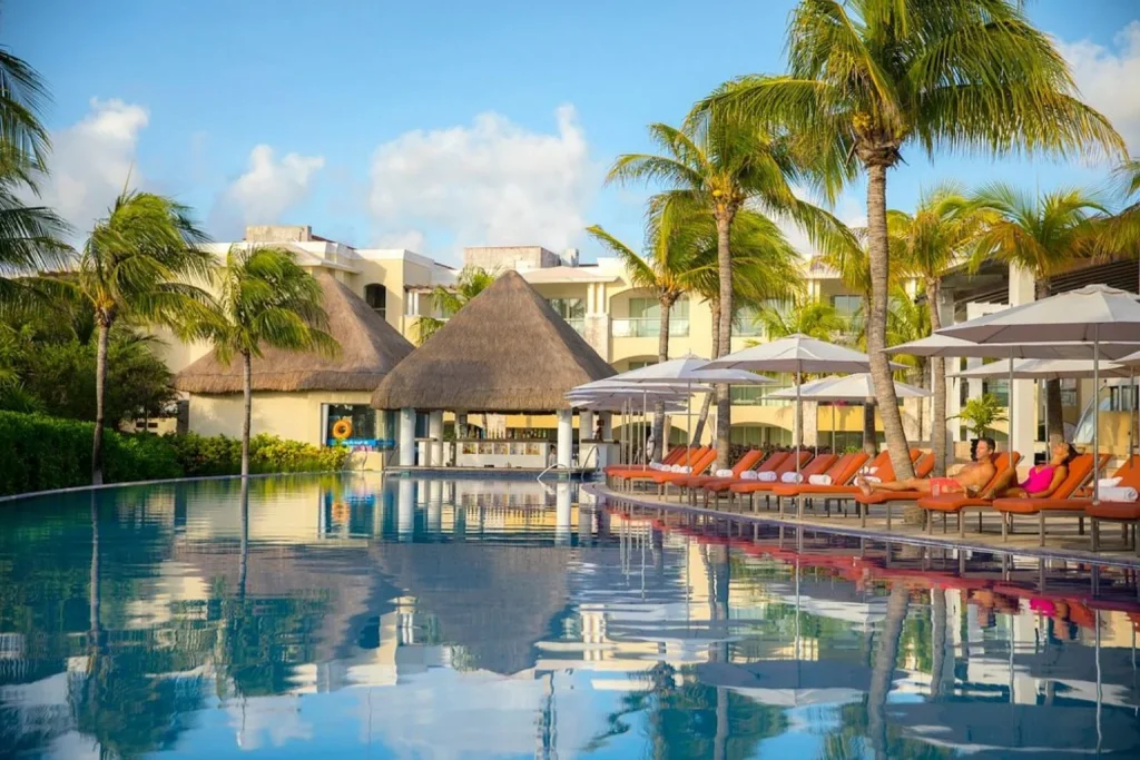 Main swimming pool with a swim-up bar, palm trees, and sun loungers at The Grand at Moon Palace Cancun in Cancún, Mexico.