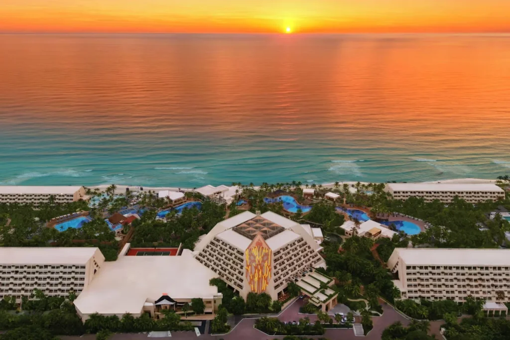 Aerial view of a beachfront resort with tropical gardens and swimming pools at sunset at Grand Oasis Cancun in Cancun