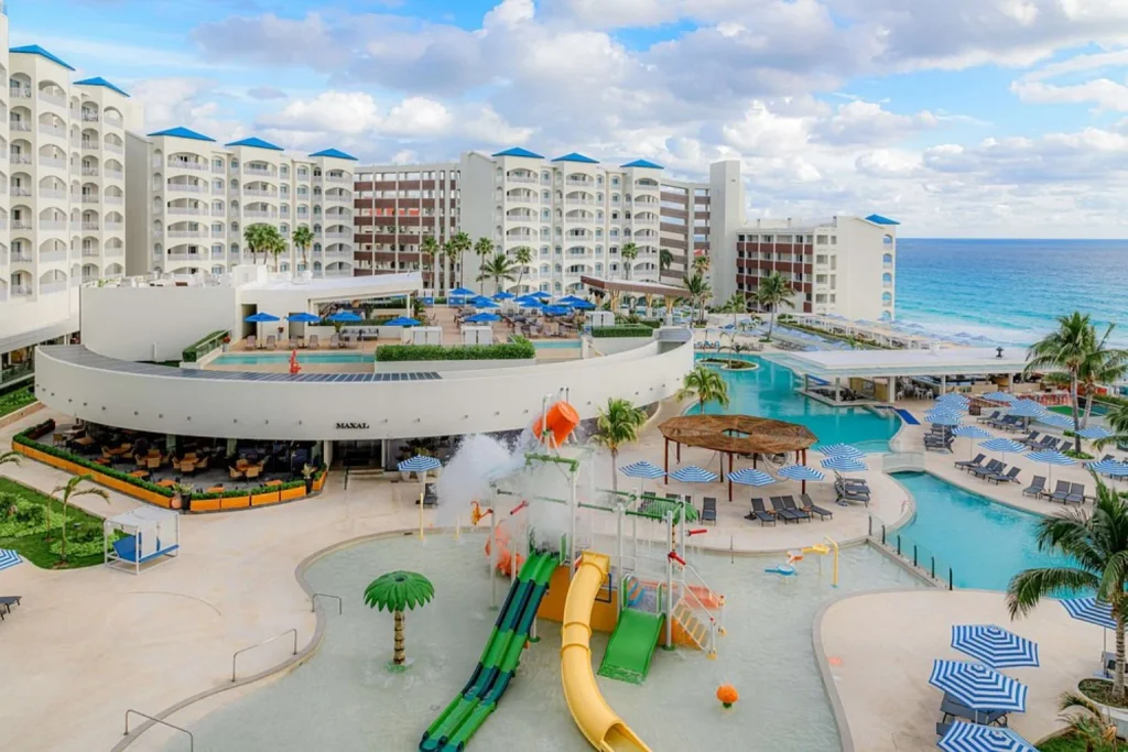 Family pool area with water slides, splash zone and Caribbean Sea views at Hilton Cancun Mar Caribe in Cancun