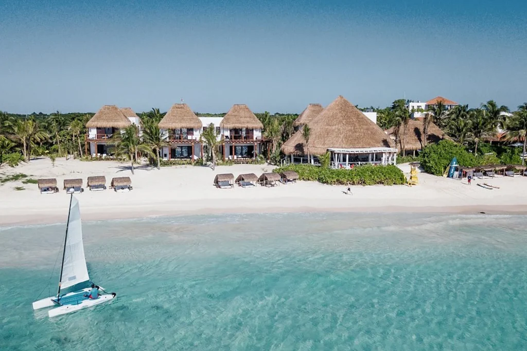 Aerial view of Hotel Esencia on the beachfront in Xpu-Ha, Riviera Maya, Mexico, with white sand and turquoise Caribbean waters.