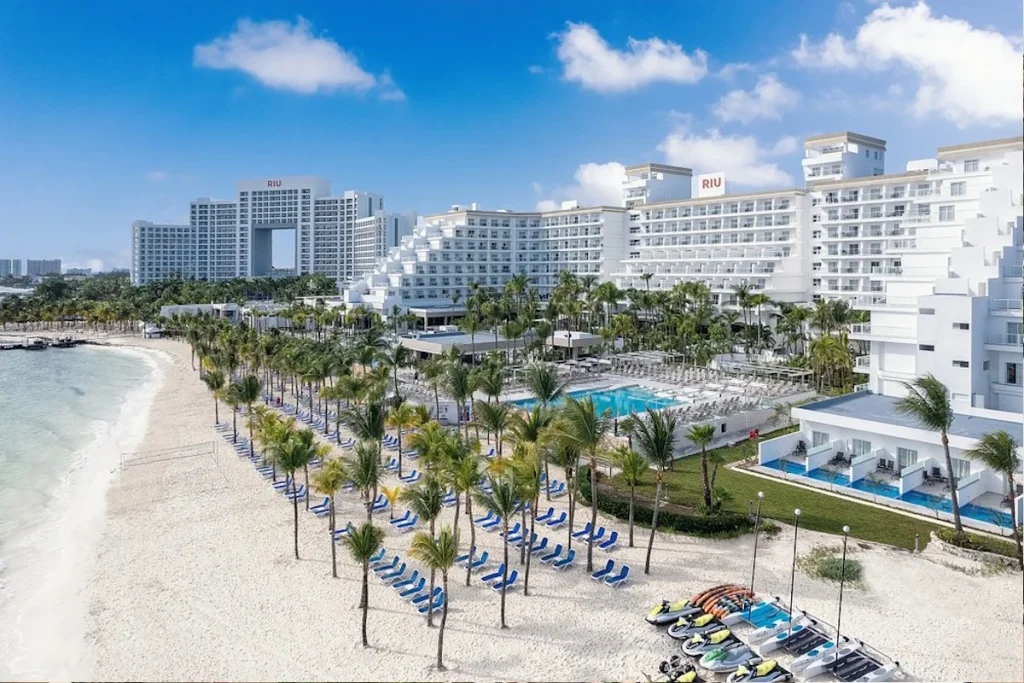 Aerial view of the beachfront, swimming pools, and white sand beach at Hotel Riu Caribe in Cancún.