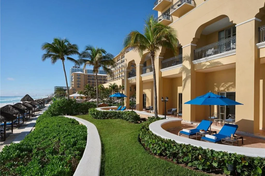 Beachfront exterior of Kempinski Hotel Cancún with palm trees and ocean views.