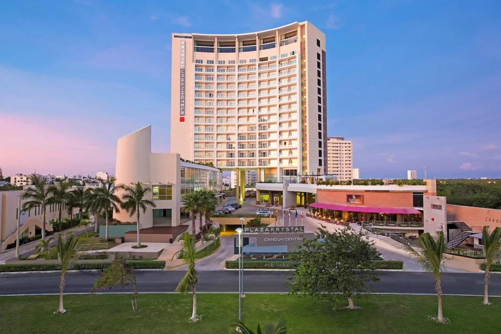 Modern high-rise hotel exterior with palm trees and main entrance at Krystal Urban Cancun Centro in Cancun