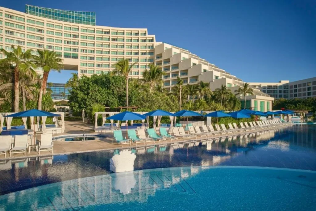 Oceanfront main swimming pool with sun loungers and palm trees at Live Aqua Beach Resort Cancun in Cancún, Mexico.
