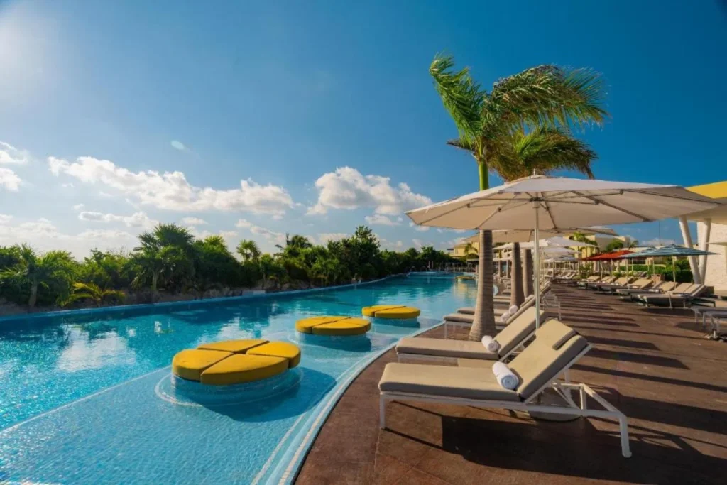 Infinity swimming pool with sun loungers, umbrellas, and tropical landscaping at Moon Palace The Grand Cancun in Cancún, Mexico.