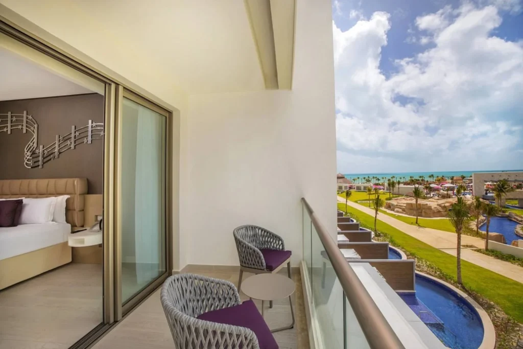 Ocean-view balcony with seating overlooking the resort pool at Planet Hollywood Cancun
