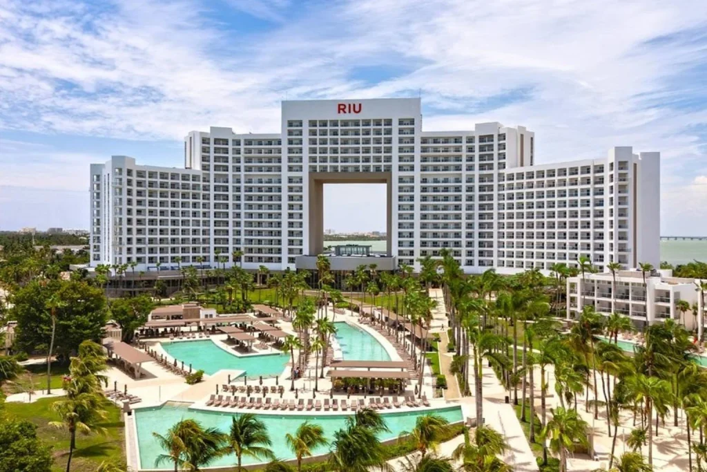 Aerial view of the resort with multiple swimming pools, spacious sun terraces and tropical palm gardens at Riu Palace Peninsula in Cancun.