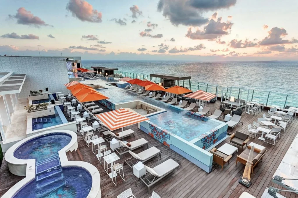 Rooftop pool with loungers and panoramic ocean views at Royalton CHIC Cancun.