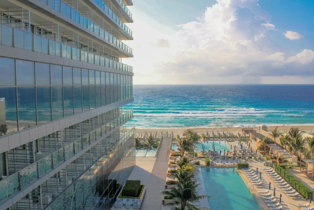 Elevated view of the infinity pool, beachfront terrace, and turquoise Caribbean Sea at Secrets The Vine Cancun in Cancún, Mexico.