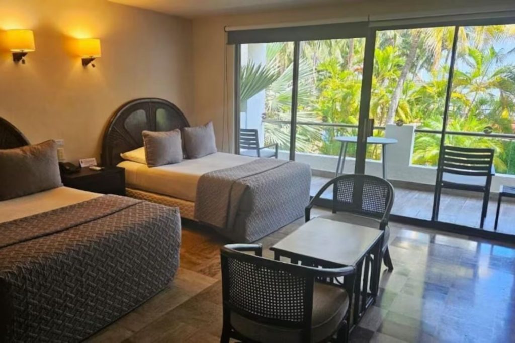 Junior suite with twin beds and a private balcony overlooking tropical gardens at Sina Suites Cancun in Cancun, Mexico.