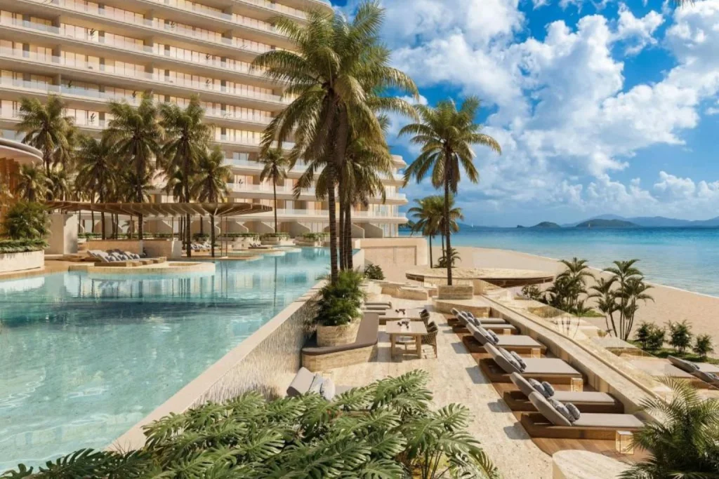 Oceanfront infinity pool with beachfront sun loungers and tropical landscaping at The St. Regis Costa Mujeres Resort in Costa Mujeres, Mexico.