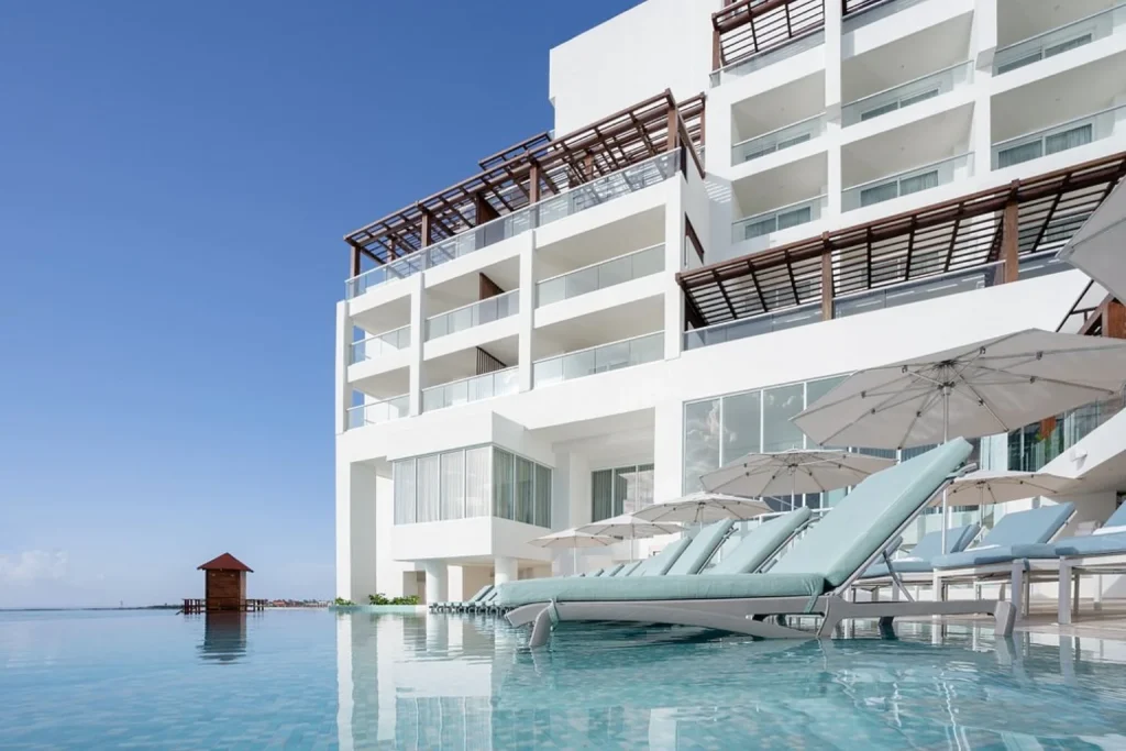 Infinity pool with ocean view and sun loungers at Sun Palace Cancun in Cancun