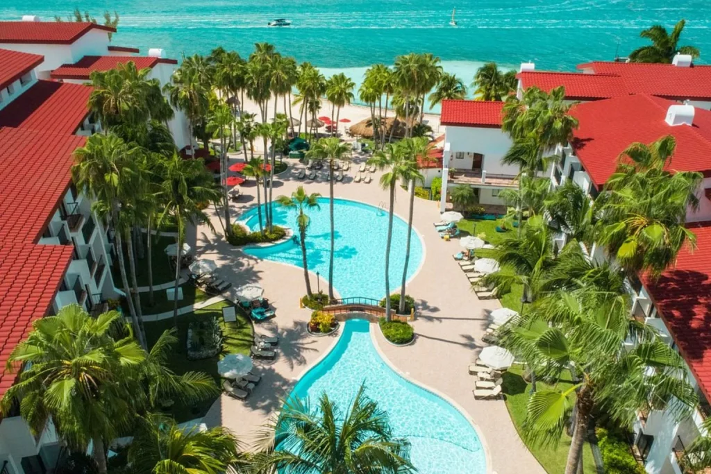 Aerial view of the oceanfront pool complex and tropical gardens at The Royal Cancun All Suites Resort in Cancún, Mexico.