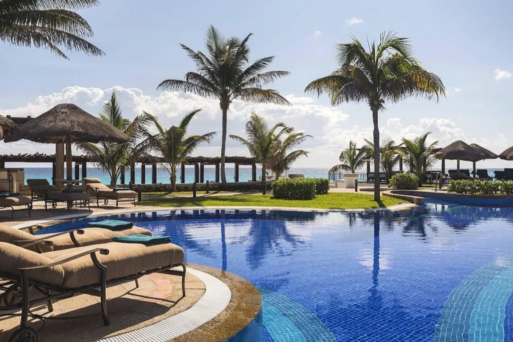 Oceanfront swimming pool with palm trees, loungers, and Caribbean Sea views at W Costa Mujeres in Costa Mujeres.